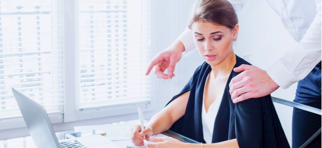 Woman at work looking uncomfortable with a man's hand on her shoulder