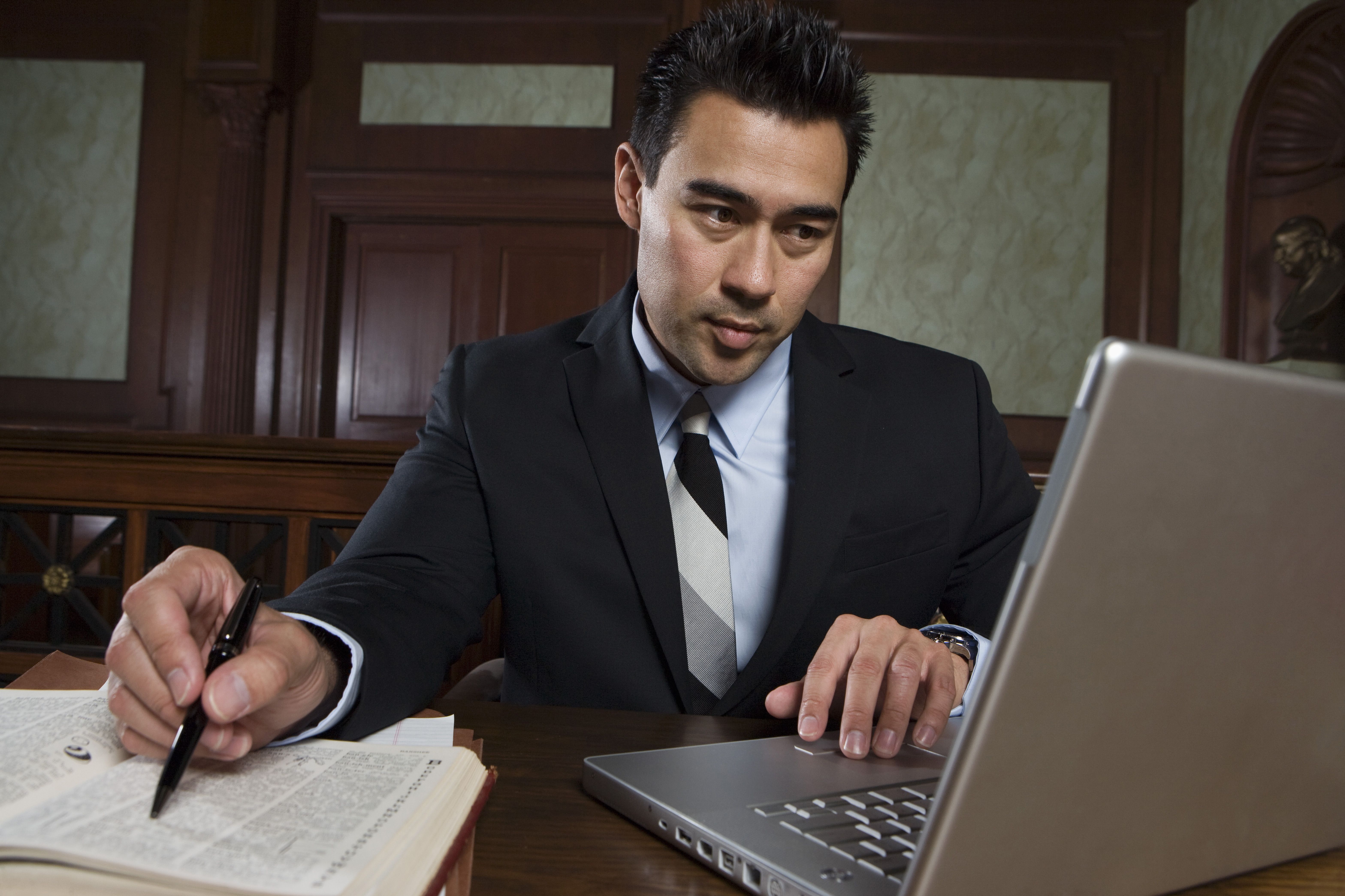 man taking notes and looking at his laptop